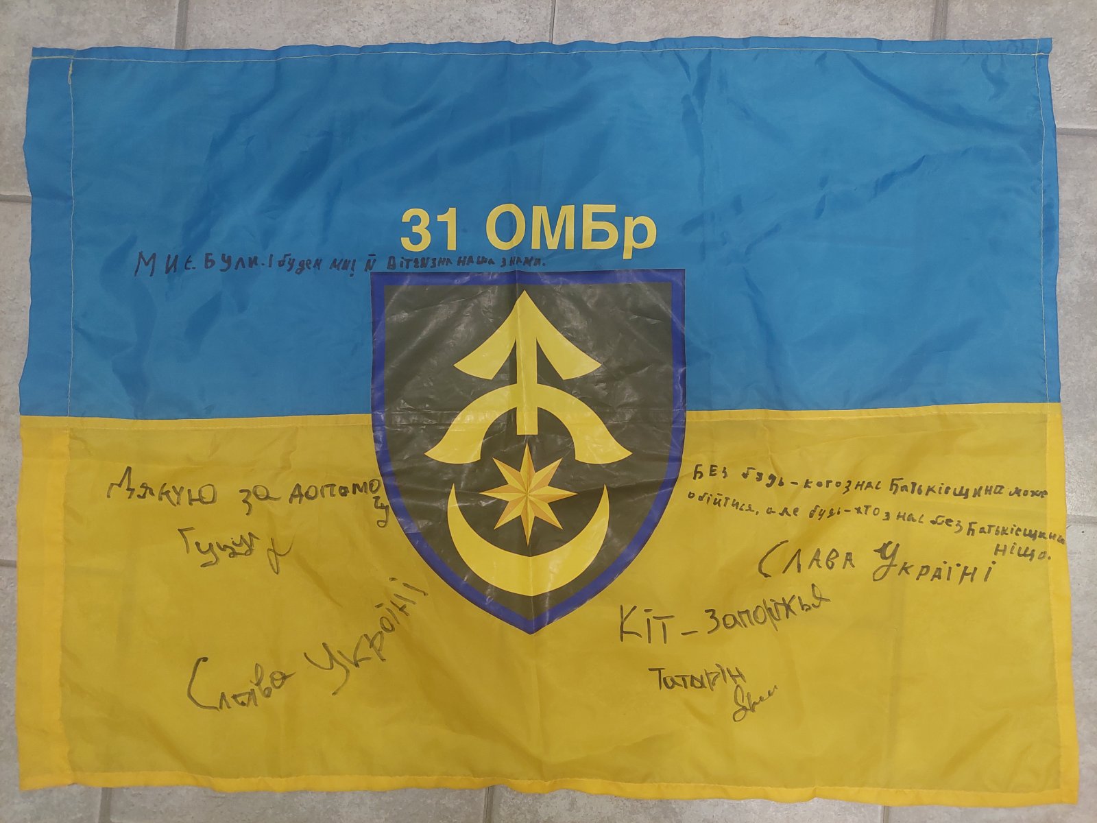 Ukrainian flag signed by fighters of 31st Mechanized Brigade